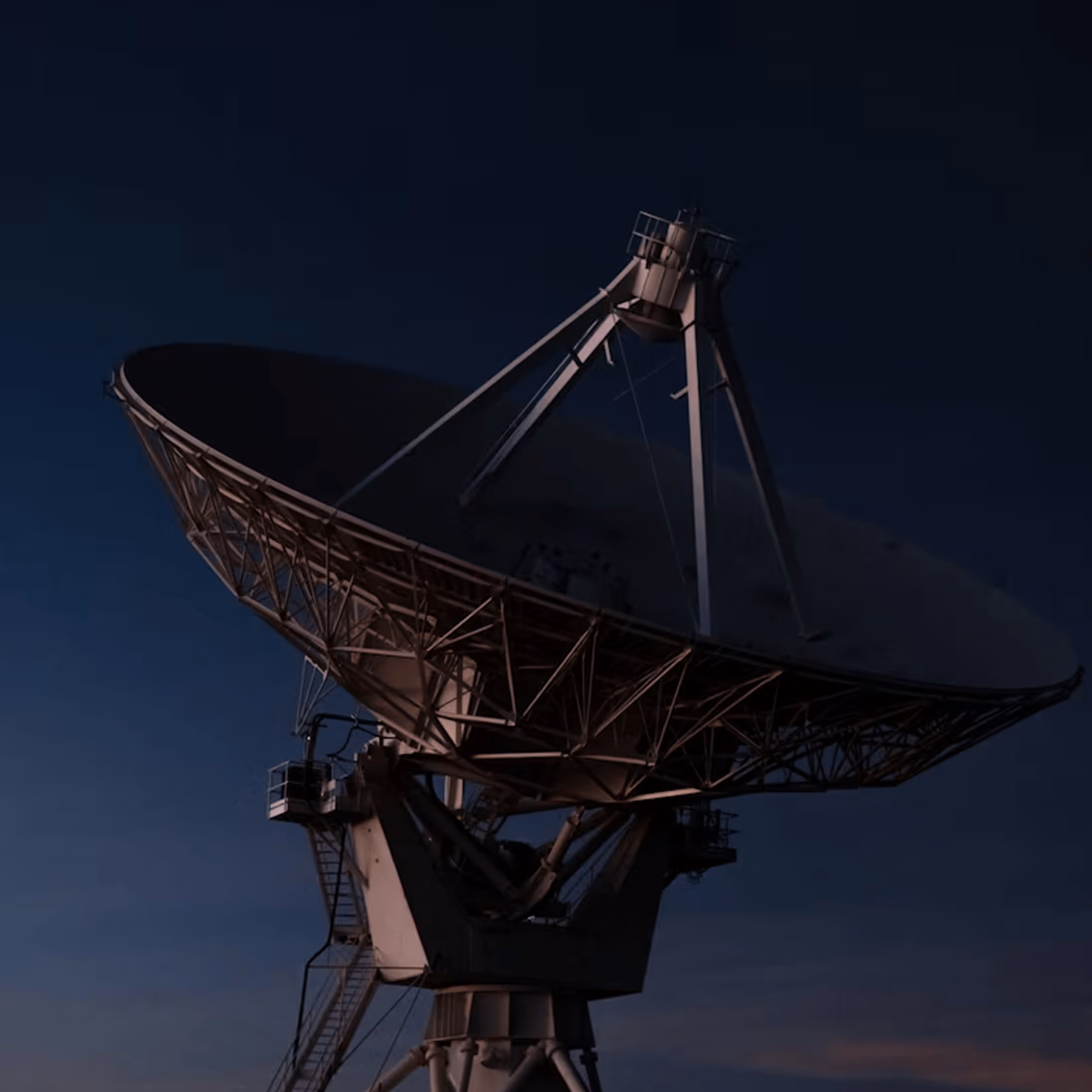 Large satellite dish antenna against a dark evening sky.