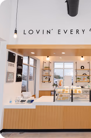 Bright modern coffee shop counter with pastries and minimalist decor under partial sign reading Lovin' Every