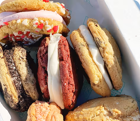 Box with assorted ice cream sandwich cookies filled with white and pink cream.