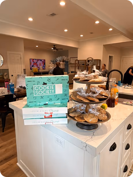 Kitchen island with stacked Cookie Society boxes and a tiered tray of wrapped cookies.