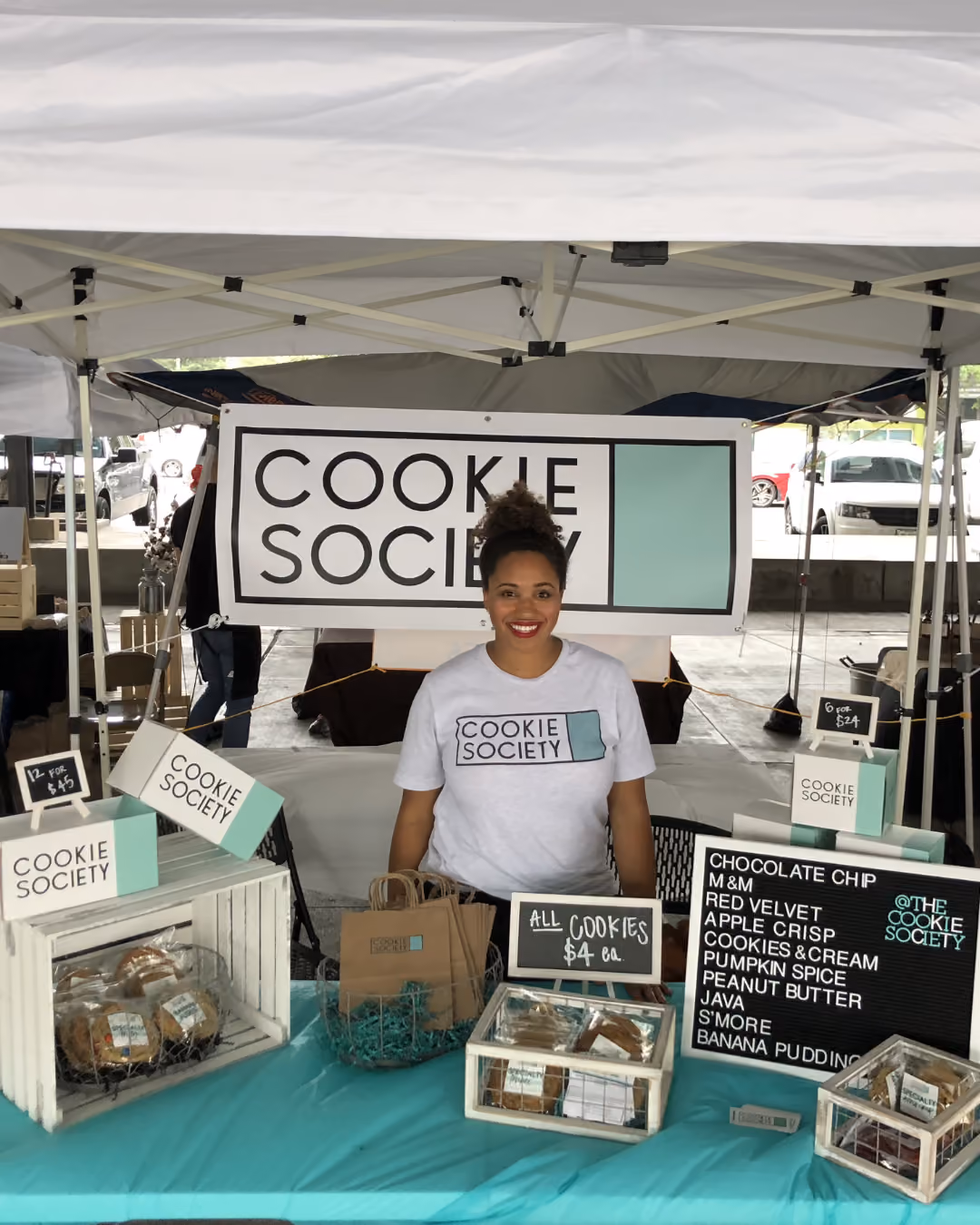 Cookie Society farmers market tent with boxed cookies and a flavor menu board