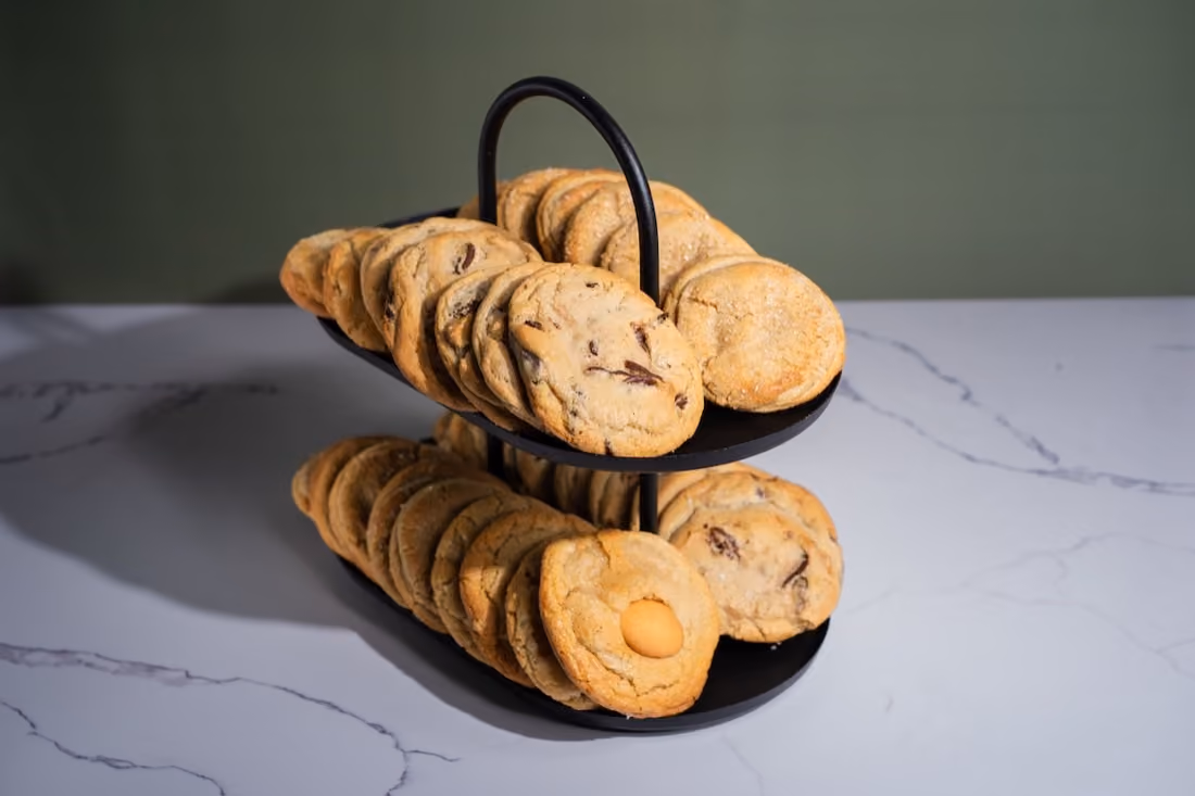 Chocolate chip cookies stacked on a black tiered stand