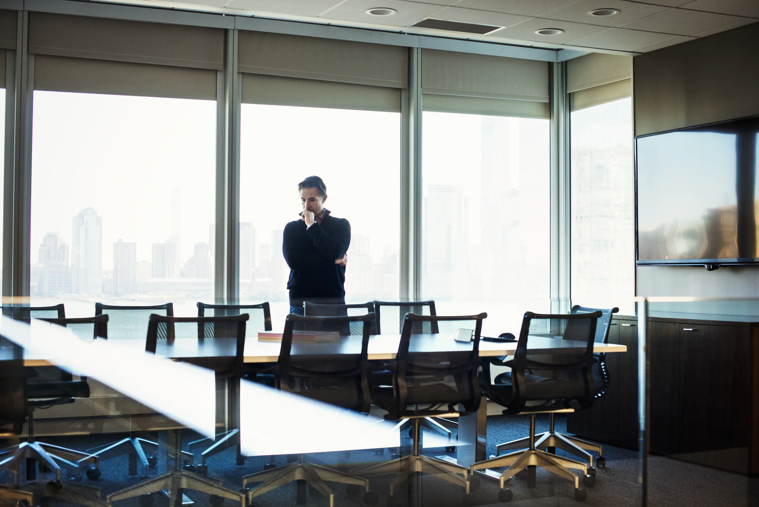 Pensive businessman standing beside a conference room window