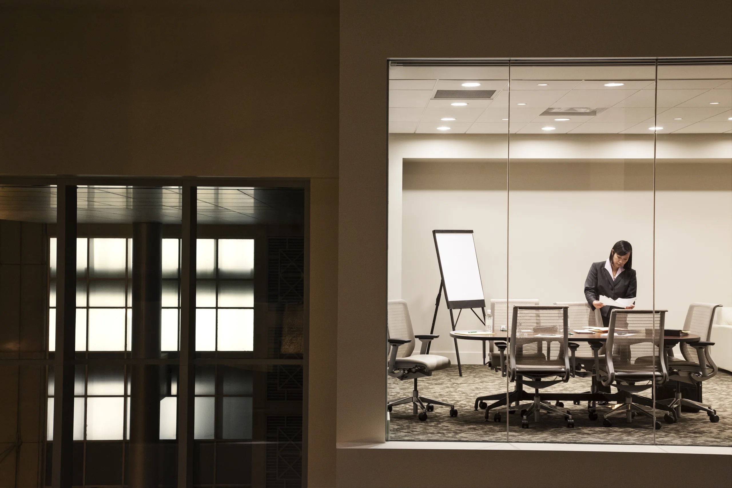 View into a modern glass conference room lit up at night
