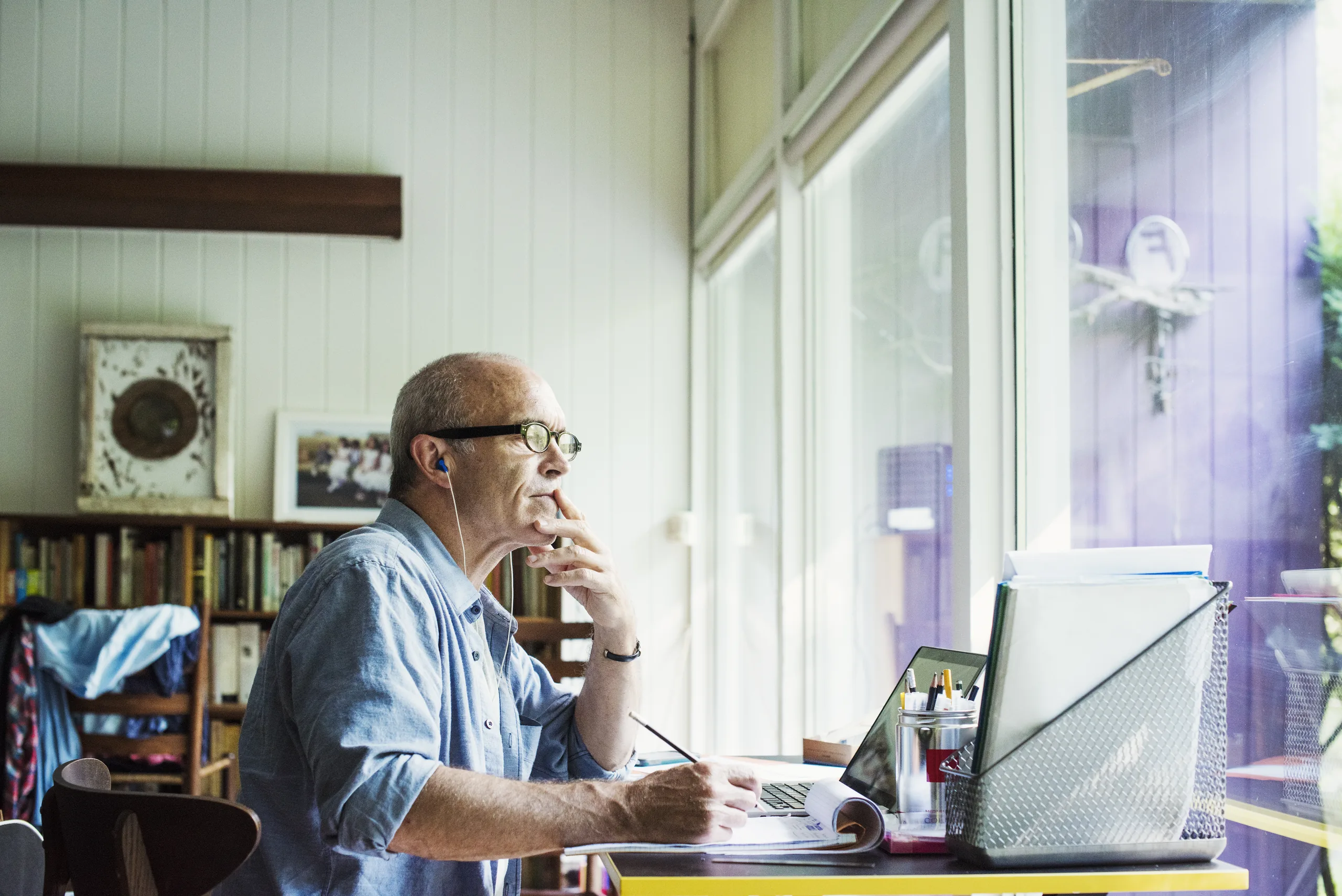 Man working from home, pausing in thought by the window