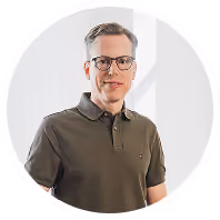 Mann mit Brille in olivgrünem Poloshirt vor hellem Hintergrund.