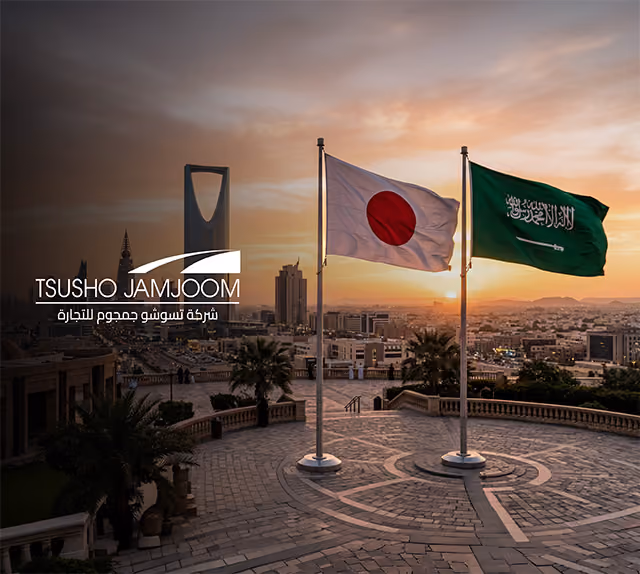 Japanese and Saudi Arabian flags on poles with a cityscape and sunset in the background.