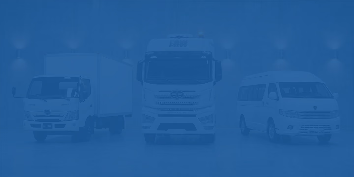 Three white commercial vehicles parked indoors: a box truck, a large semi truck, and a passenger van.