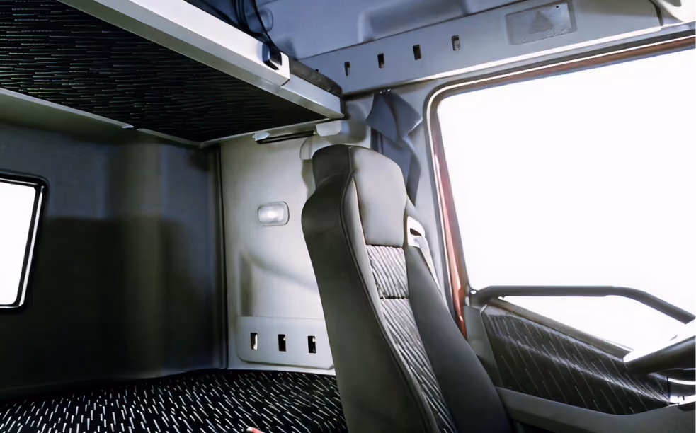 Interior of a truck cabin with a single black driver seat and window on the right side.