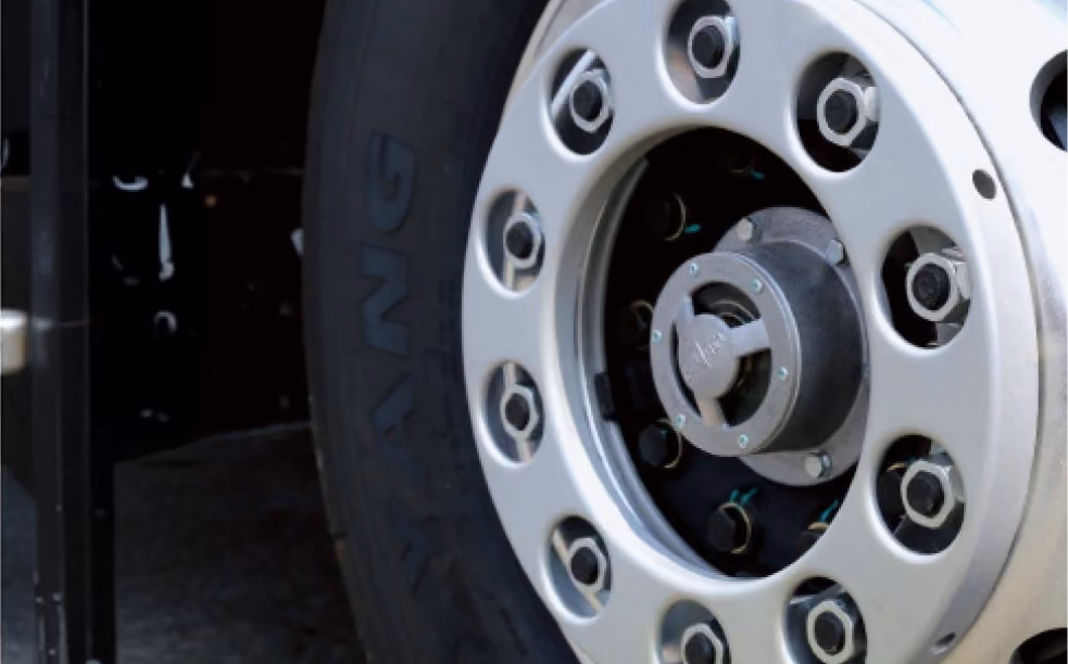 Close-up of truck wheel with tire labeled YANG and a silver hubcap with multiple lug nuts.