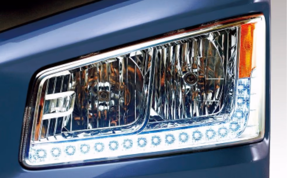 Close-up of a blue car's rectangular headlight with chrome and LED detailing.