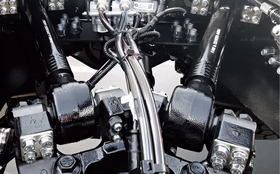 Close-up of hydraulic system with black metal pipes, bolts, and connectors in a mechanical setup.