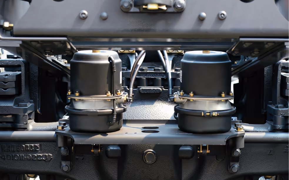 Close-up of two black air brake chambers on a heavy vehicle chassis.