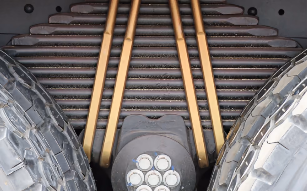 Close-up of mechanical parts between two large tires, showing metal rods and circular components.