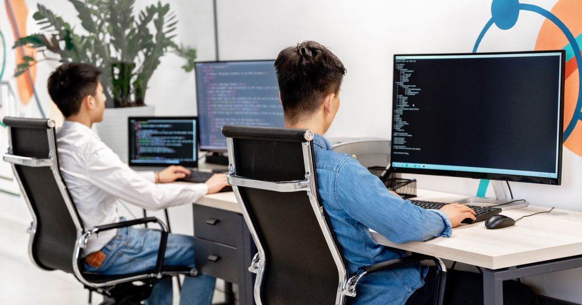 Software engineers collaborating at monitors in a modern technology office