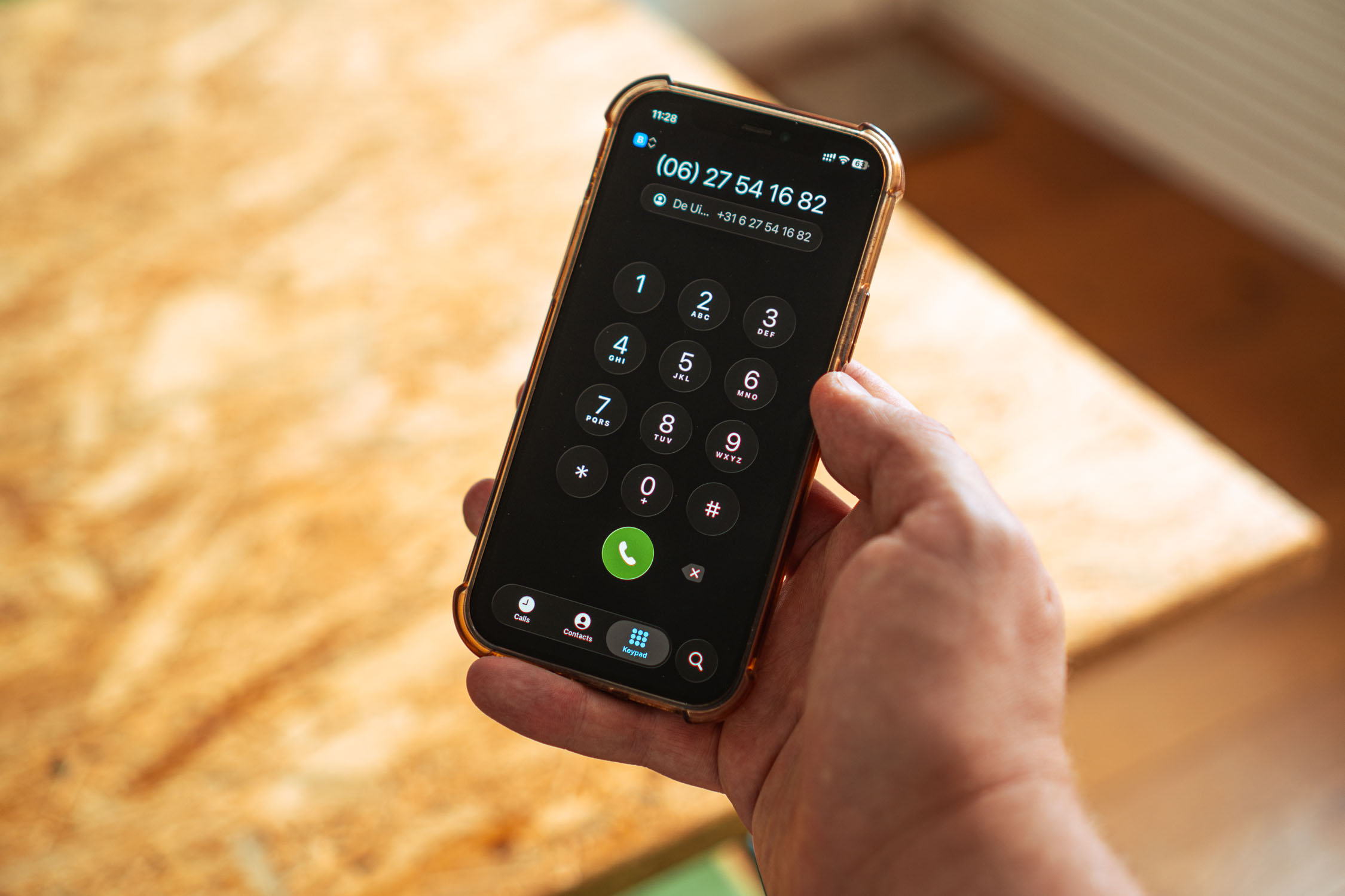 Hand houdt smartphone met nummerblok en telefoonnummer +31 6 27541682 op scherm.