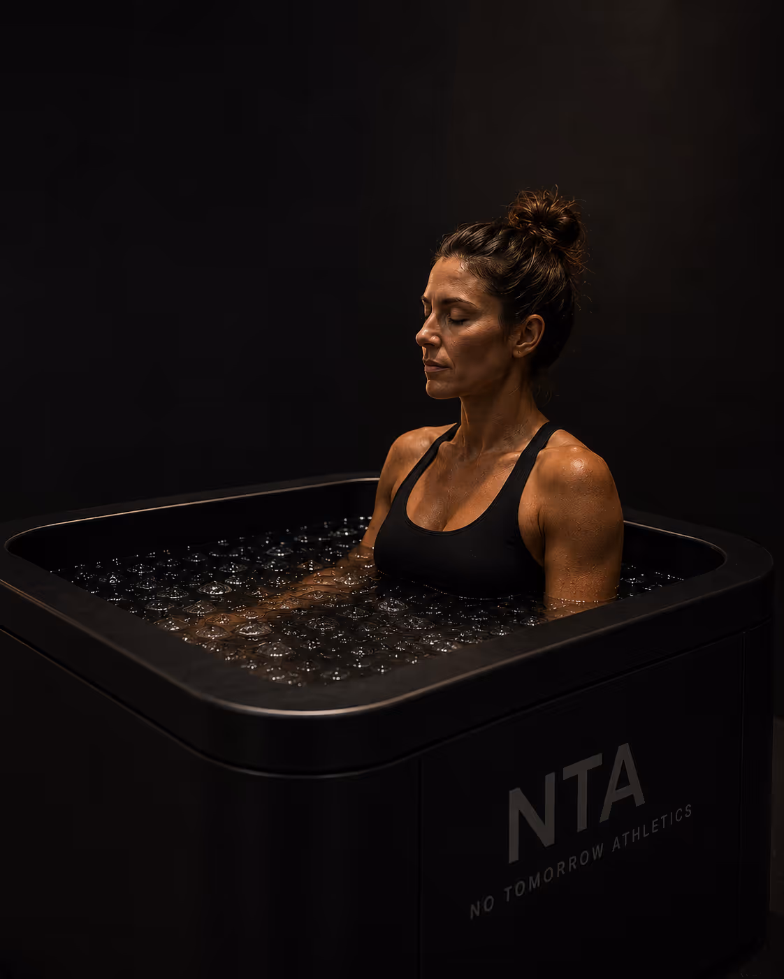A woman sitting in a cold plunge post-workout. 