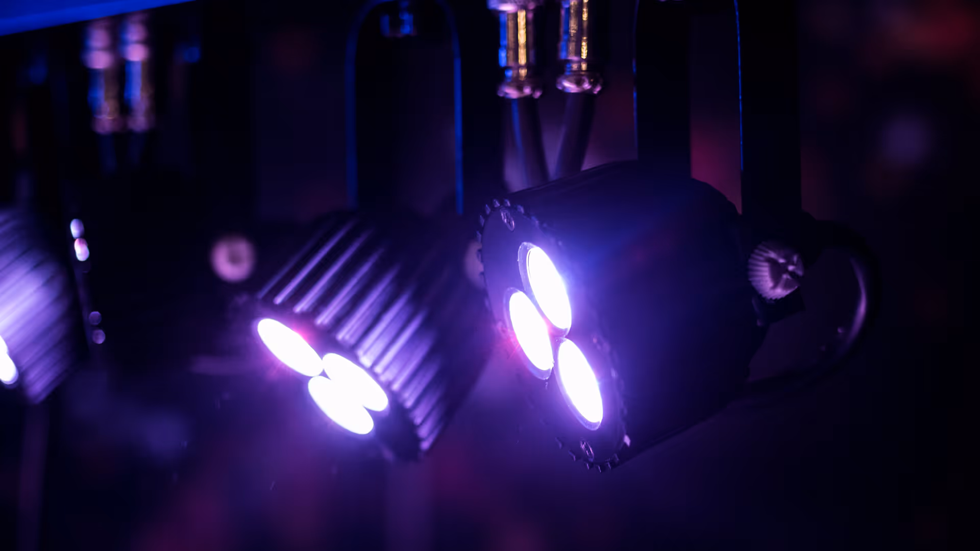 Close-up of two purple LED stage lights glowing in a dark environment.