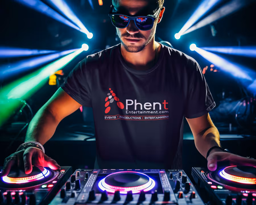 DJ wearing sunglasses and Phent Entertainment shirt mixing music with colorful stage lights behind him.