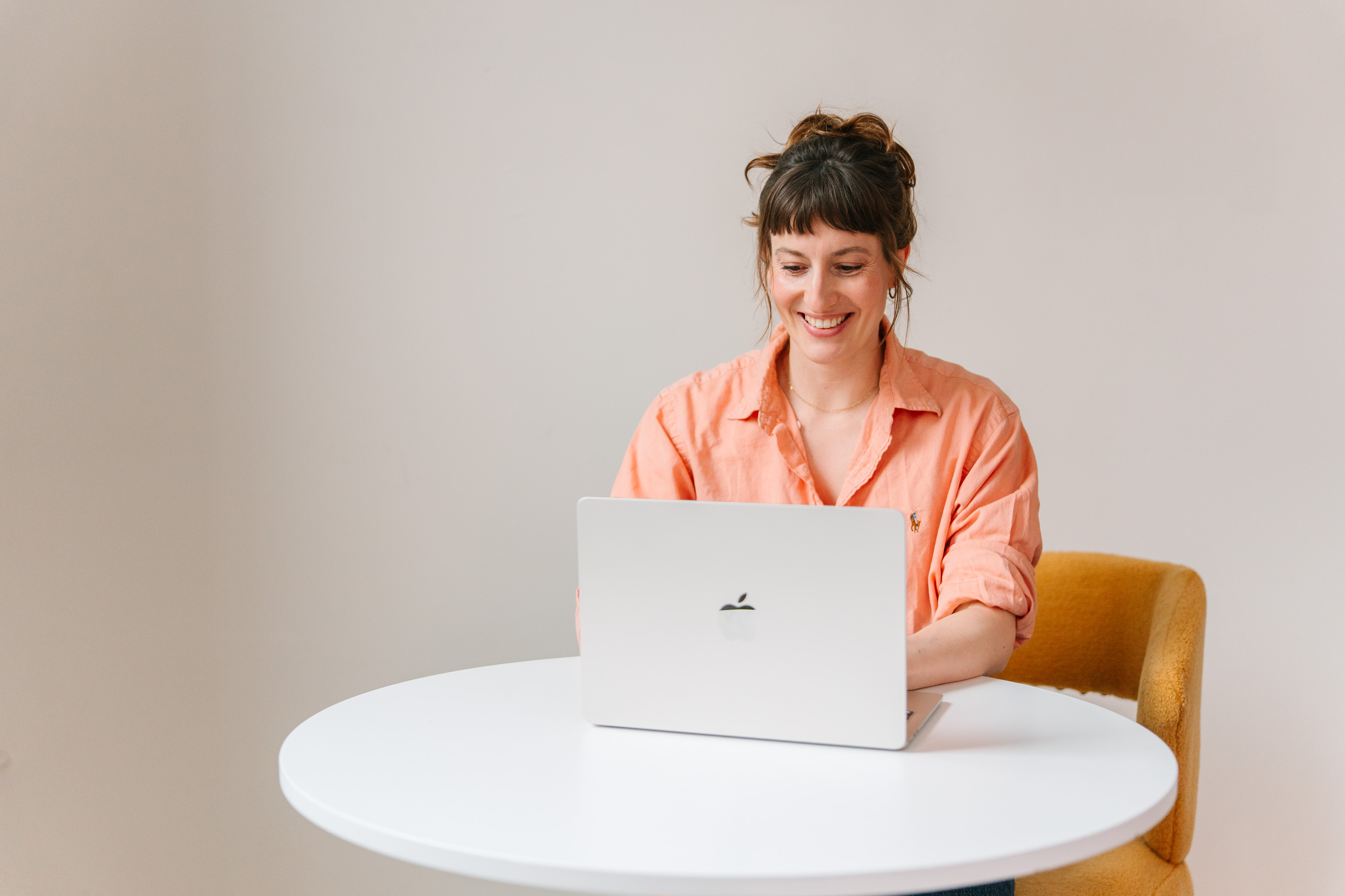 Deanne Vincent working at a laptop in an orange shirt