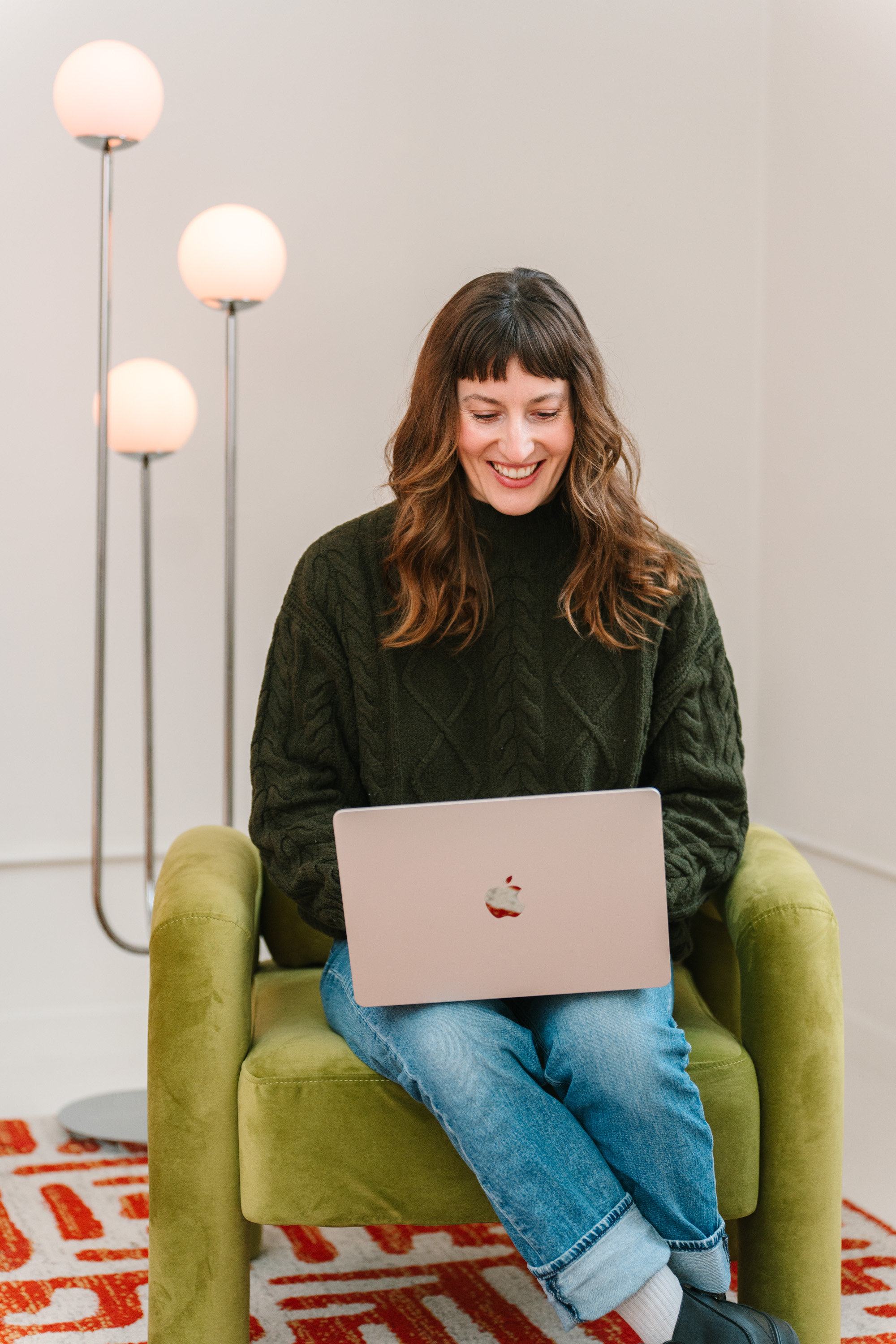 Deanne working on a laptop in a green armchair