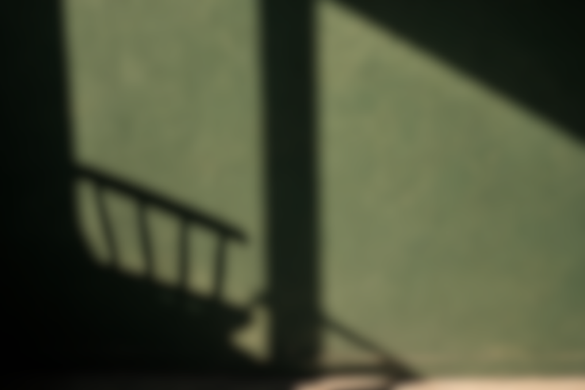 A shadow of a chair on a green wall
