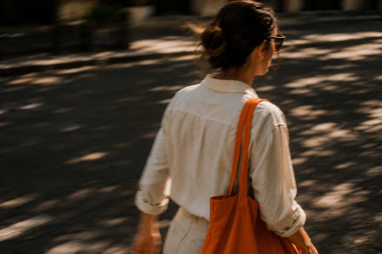 Woman walking away with an orange tote bag