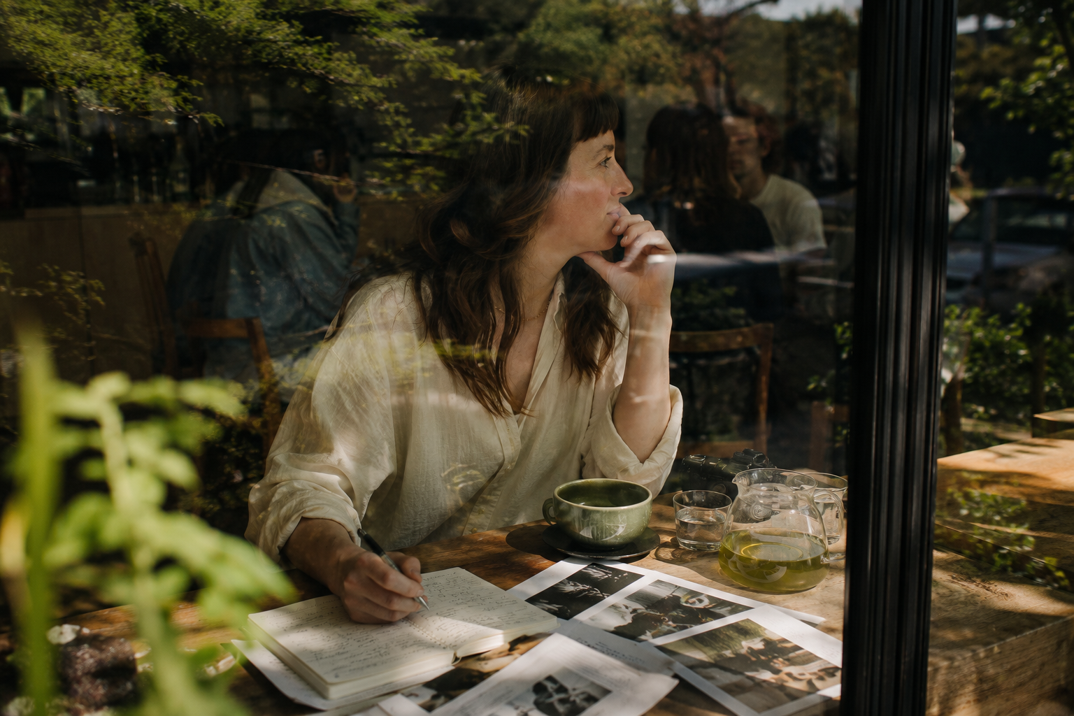 Woman planning at a café table with notes and images