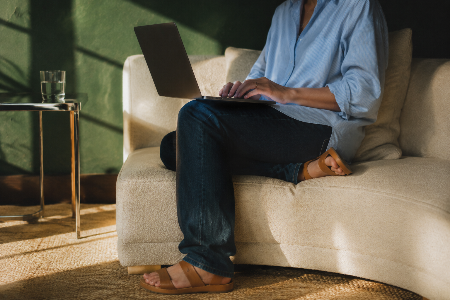 Person using a laptop while seated on a sofa