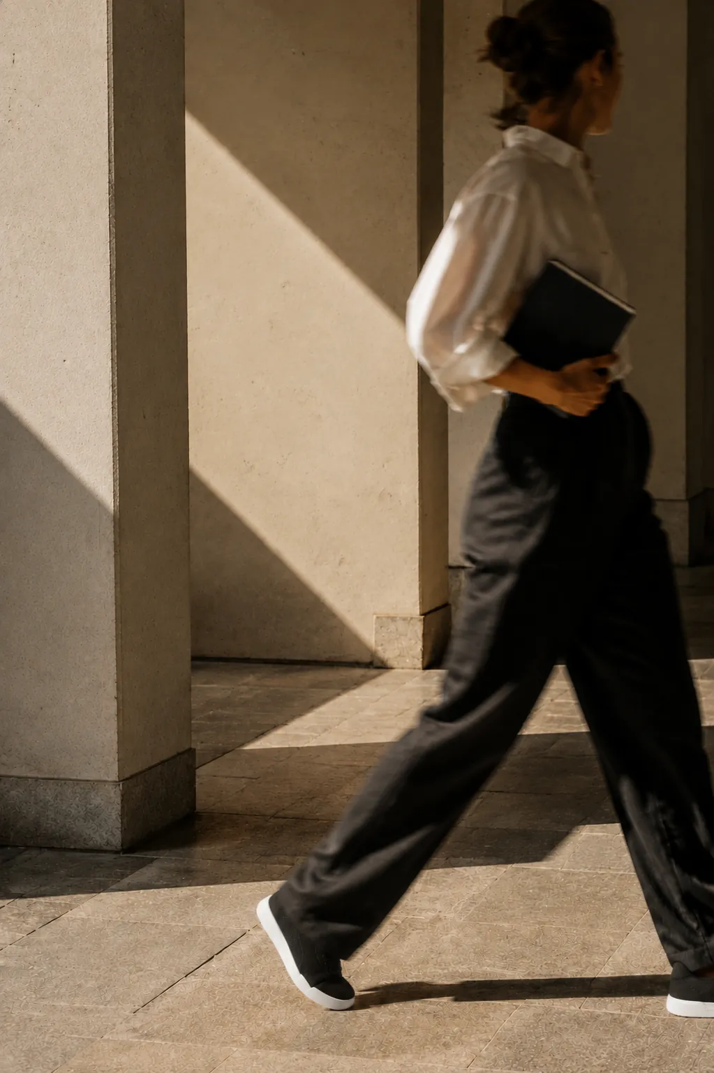 Woman walking through a sunlit colonnade