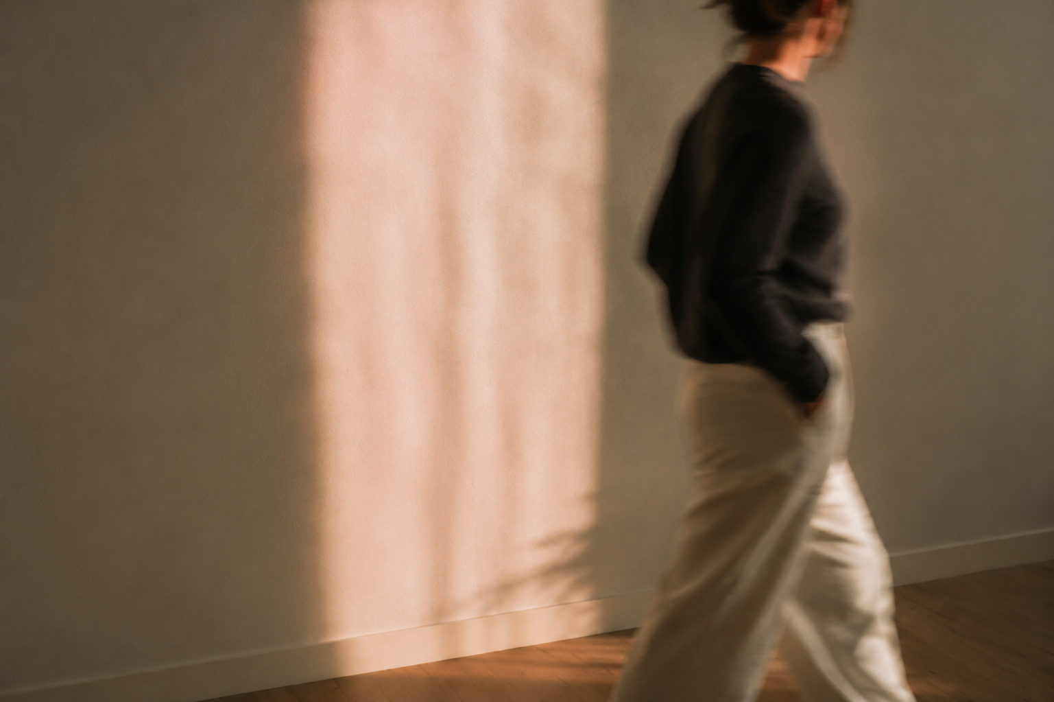 Woman moving through a softly blurred band of curtain light