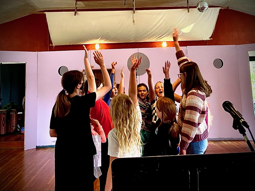 Teens with arms raised during a theatre workshop in the gallery