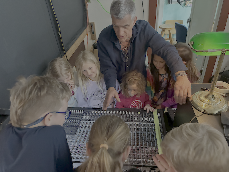Young people gathered around the sound board in the studio