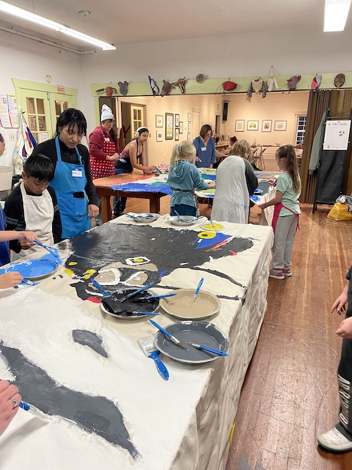 A fish printing workshop in progress, with finished prints laid out across the tables