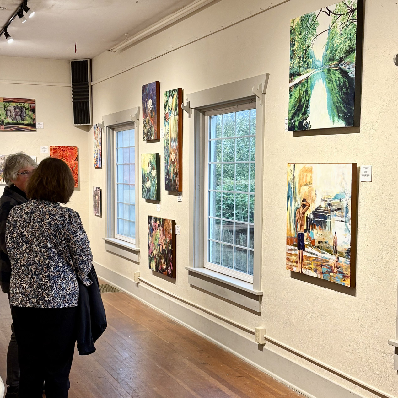 Visitors looking at framed work along the gallery wall