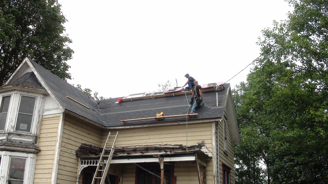 A worker on the roof of Hoquarton House during restoration, ladder against the eaves