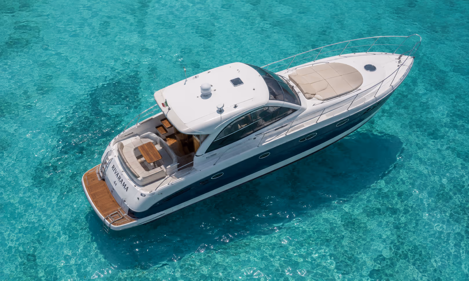 Yacht blanc nommé Rivarama A4 flottant sur une eau turquoise claire.