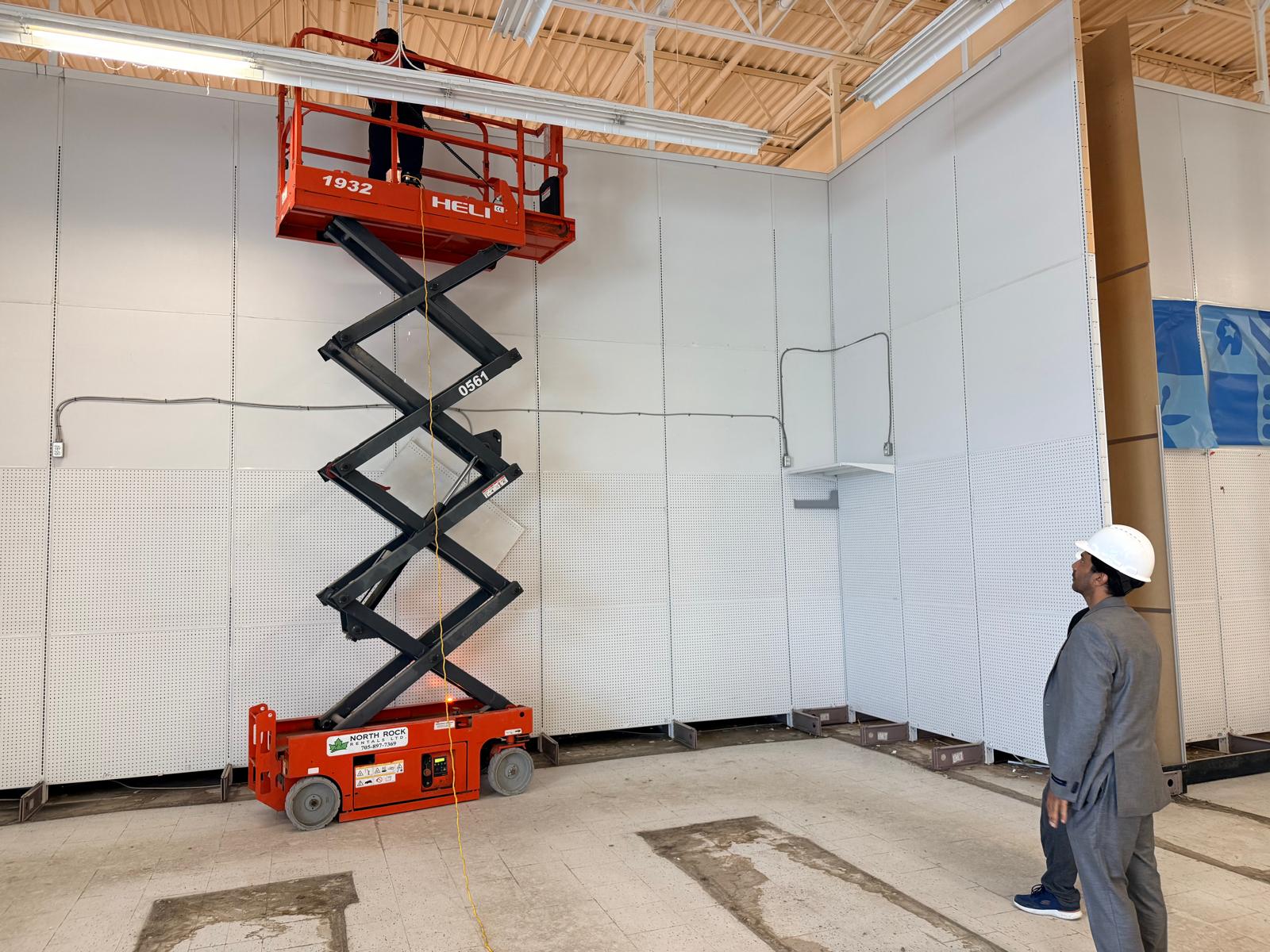 Scissor lift positioned beside tall perimeter fixtures during the Sudbury store-closing project