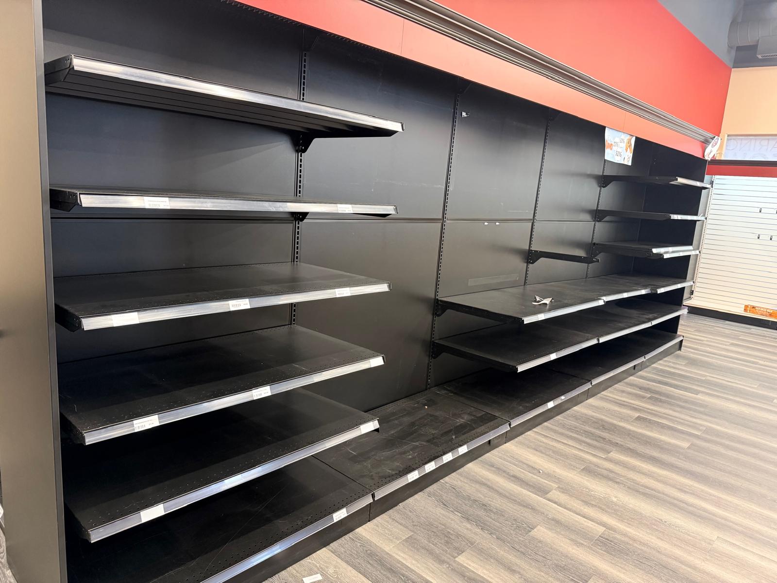 Before the cleanout: black wall shelving beneath the store's red header.