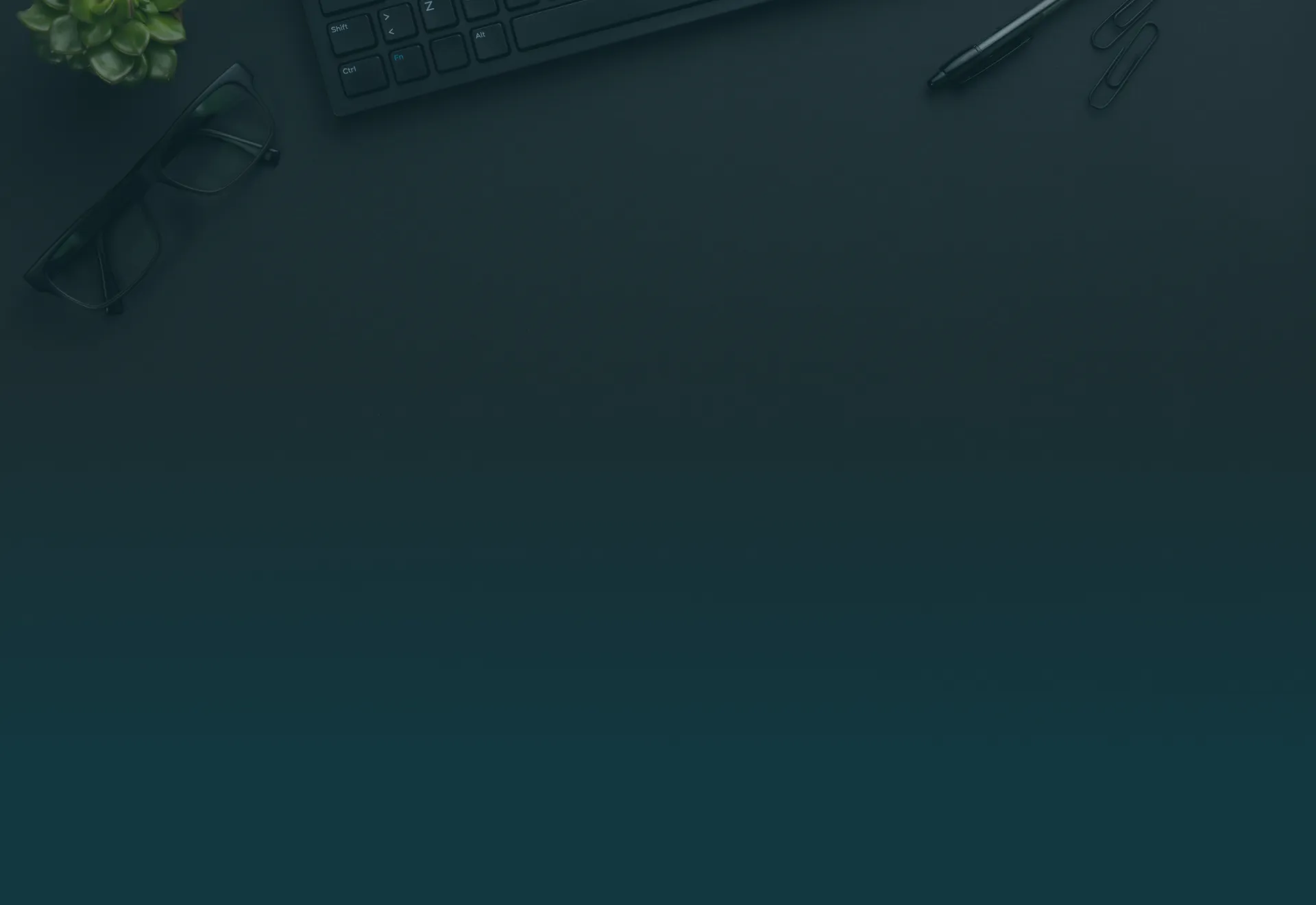 Dark desk with keyboard, glasses, pen, paper clips, and a small green succulent plant.