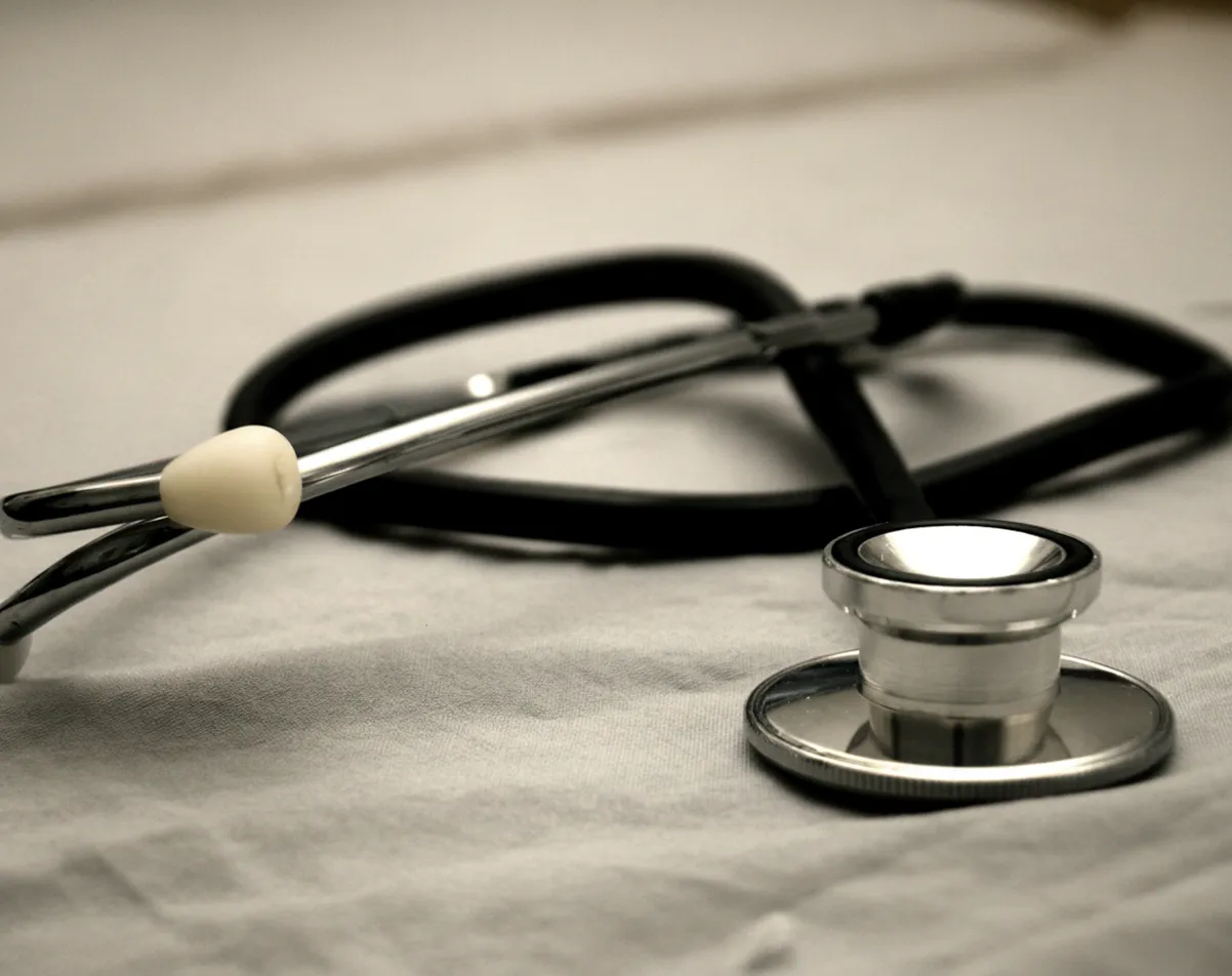 Silver and black stethoscope resting on a light gray fabric surface.
