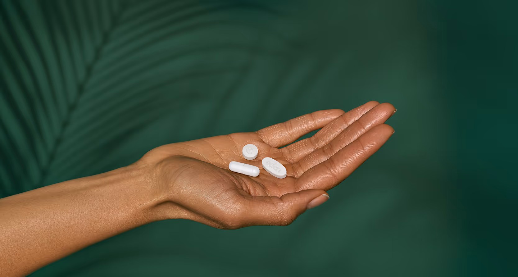 A close up of a hand holding 3 Eden pills.