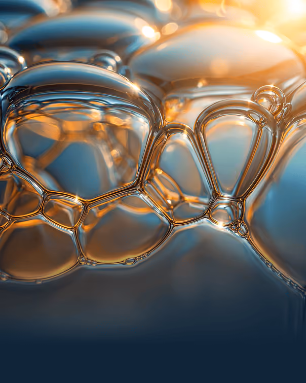 Close-up of transparent soap bubbles reflecting warm light against a soft blue background.
