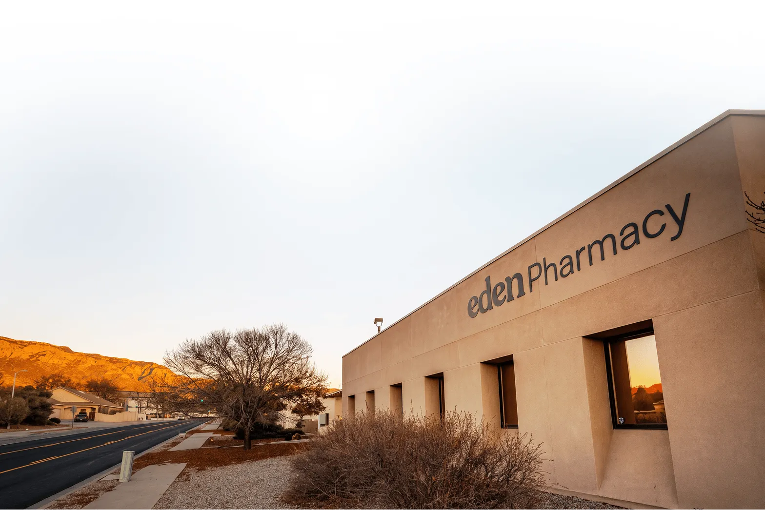 Eden Pharmacy building in Albuquerque at dusk, with mountains in the distance.
