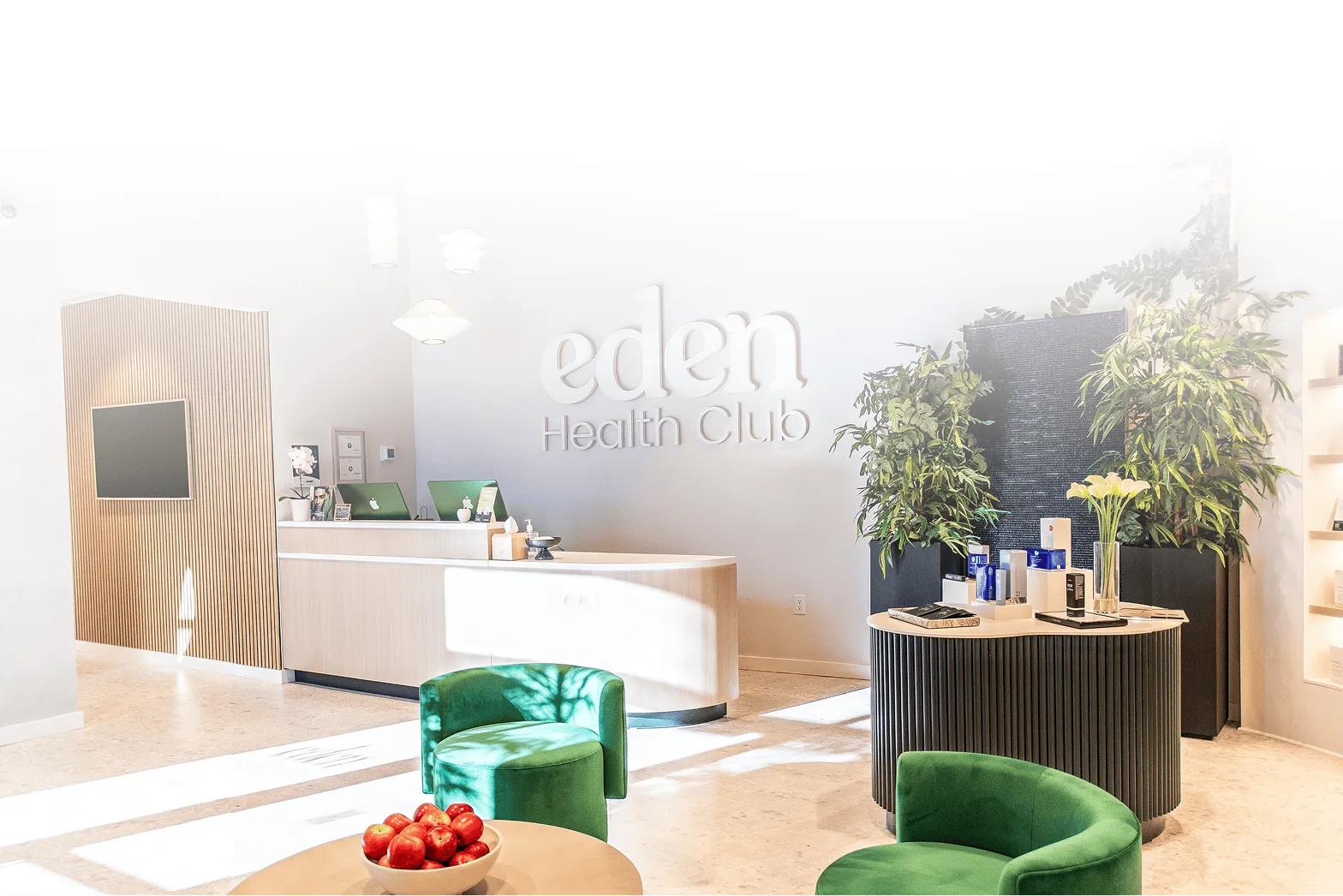 Eden Health Club lobby in Denver with green velvet chairs, a bowl of apples, and the Eden Health Club wall sign.