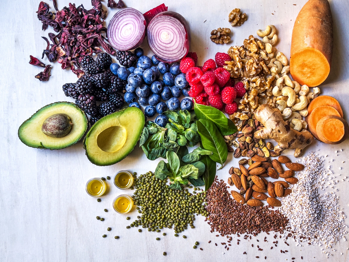 Nutrient-rich foods including nuts, seeds, berries, avocado, and vegetables for an article about nutritional deficiencies and hair loss.