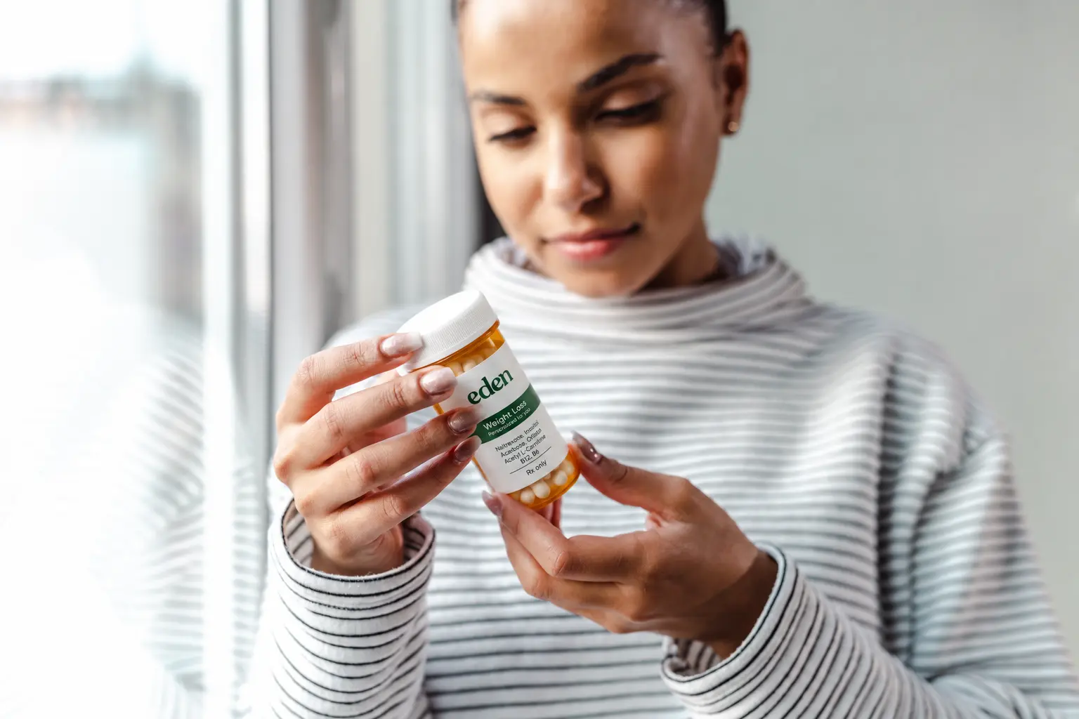Woman reviewing a prescription bottle for an article comparing Foundayo and Rybelsus as oral GLP-1 medications.