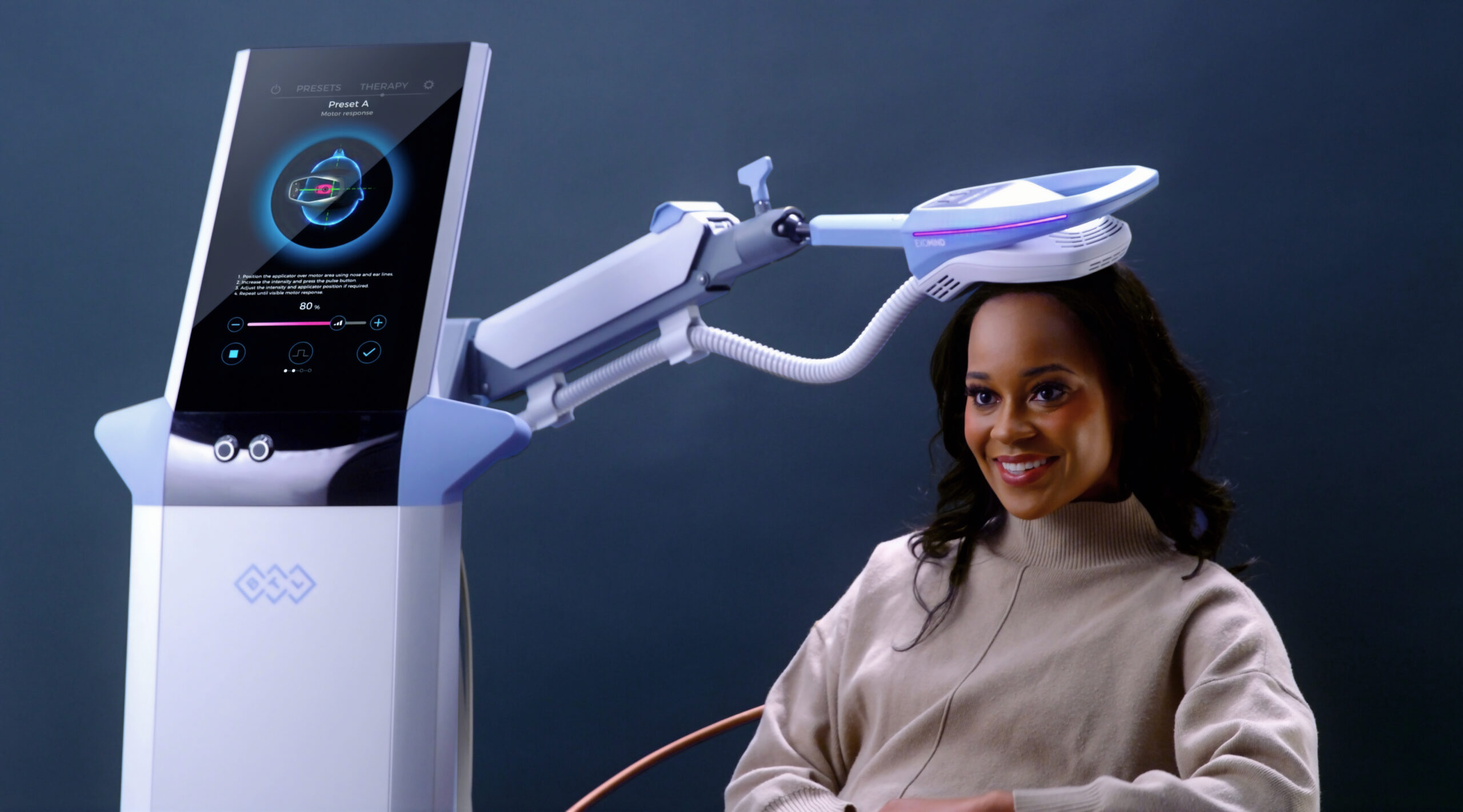 A woman sitting in front of a computer with a toothbrush on her head.