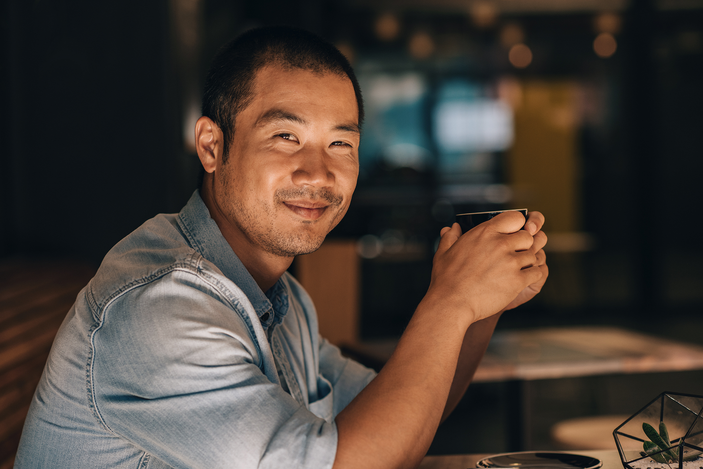A man sitting at a table holding a cell phone.