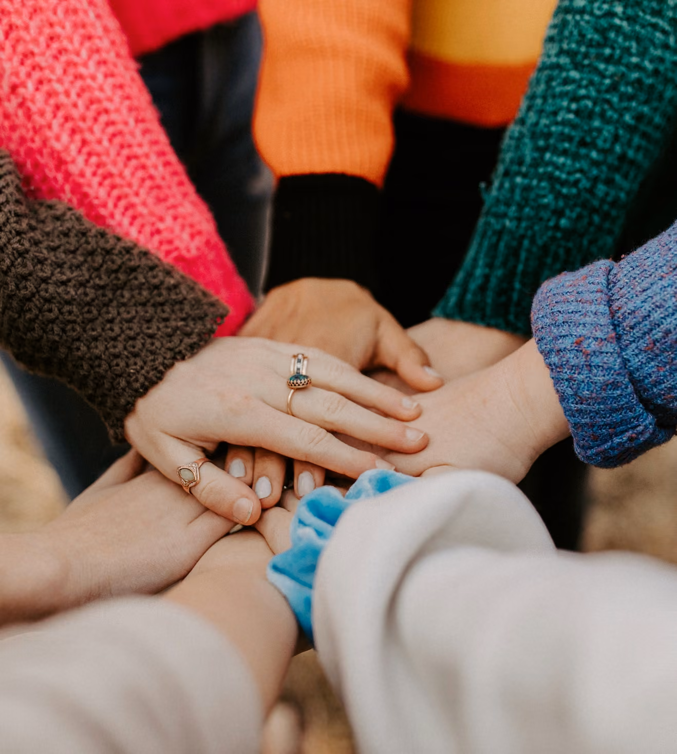 Group of people stacking their hands together in a huddle.